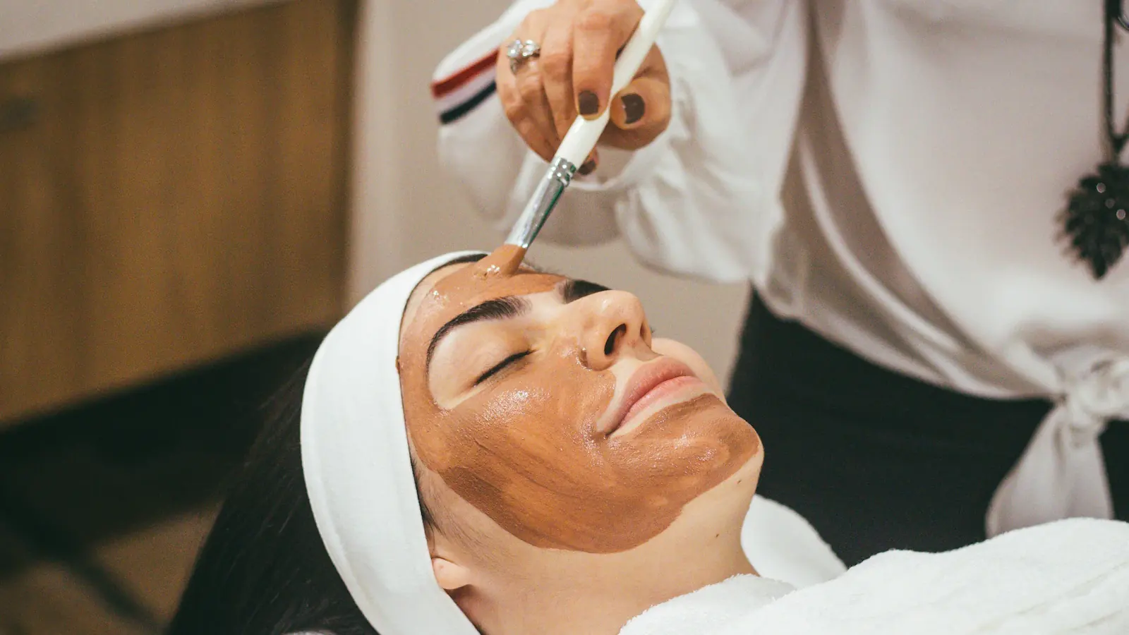 Mujer recibiendo un tratamiento facial con mascarilla en una cabina de spa