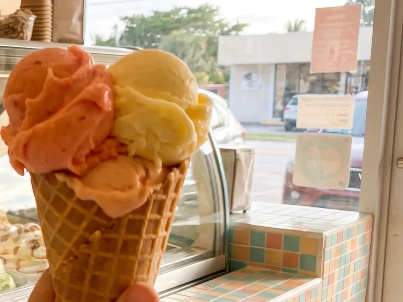 Cono de helado frente a una vitrina de sabores tropicales